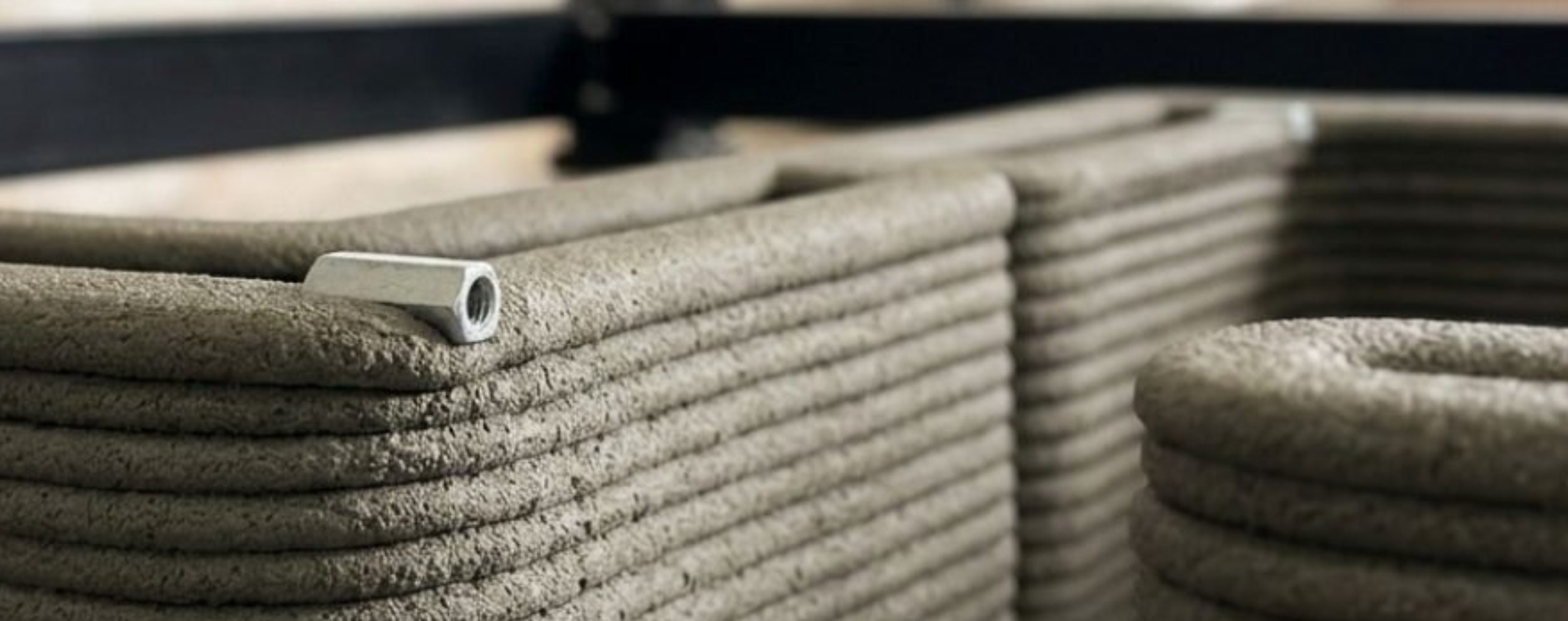 Vertico 3D printing robot creating textured concrete object on workstation